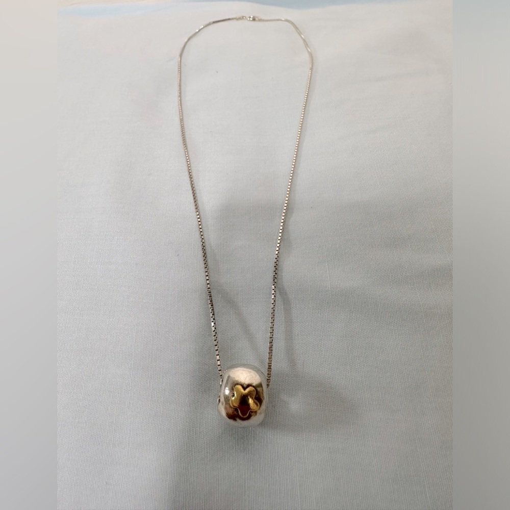 Silver pendant with gold star on the front and an arrow on the back.